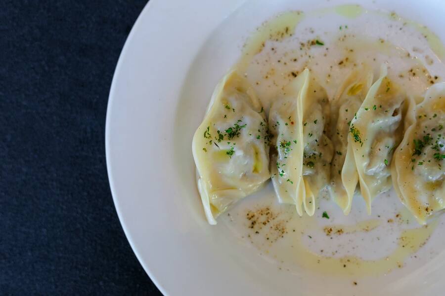 Aushak — spinach and leek dumplings under garlic yogurt and tomato sauce